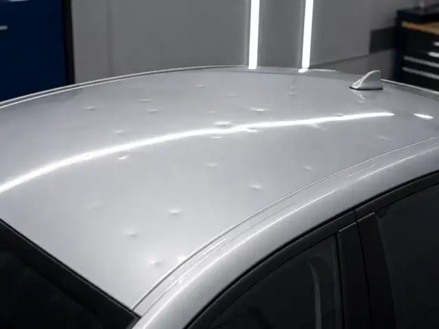 Varios impactos de granizo sobre el techo plateado de un coche